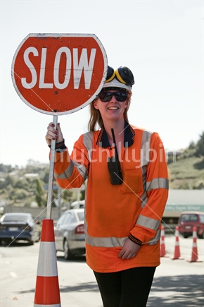 Young female traffic controller holds SLOW sign