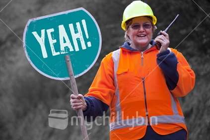 Lady traffic controller on rural road with big YEAH! sign, walkie talkie and hard hat