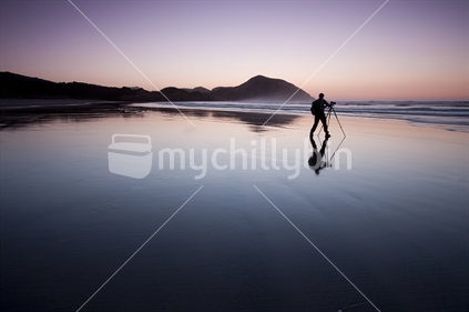 Photographer on the remote Wharariki Beach at dusk