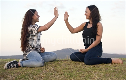 Two 18-year-old teenage girls  give each other a high five
