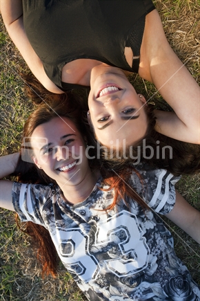 Two 18-year-old teenage girls relax on grass - aerial viewpoint