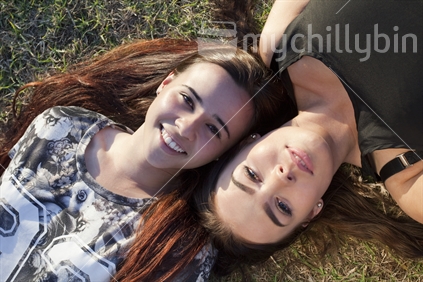 Two 18-year-old teenage girls lie on grass - aerial viewpoint - landscape