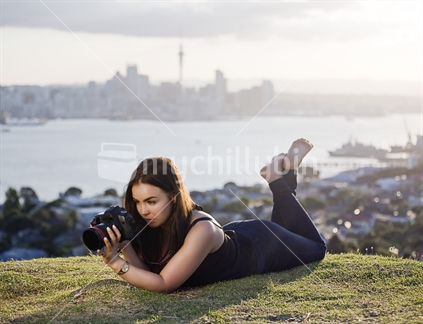 18-year-old girl with DSLR camera with Auckland City skyline beyond