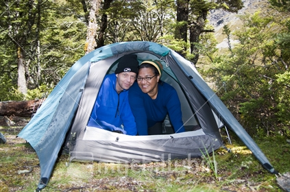 Kiwi couple inside tent in beech forest. Nelson Lakes National Park.
