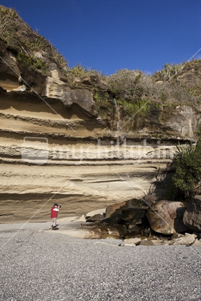 Te Miko Bay cliffs dwarf a tourist at Punakaiki, West Coast