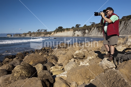 Tourist photographer with DSLR camea at Gibson Beach near Cape Foulwind, West Coast