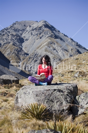 Middle-aged brunette reads a novel in red and purple polyprop tramper's clothes