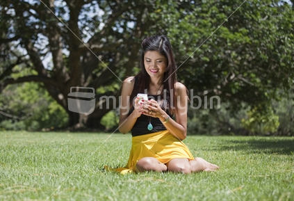 Attractive young Philippino checks her cellphone in a city park