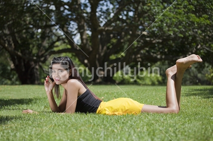 Attractive young Asian lady in Auckland Domain using her mobile phone