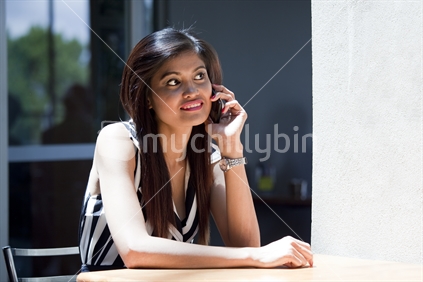 Young Asian woman eagerly uses cellphone in Restaurant