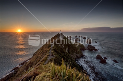 Rising sun illuminates the lighthouse on Nugget Point - Catlins coast