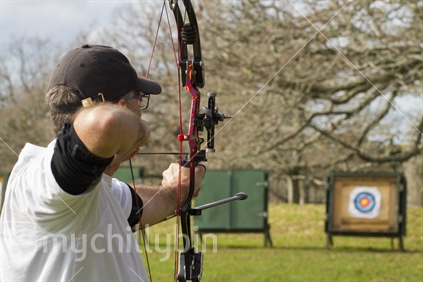 Archer taking aim at target in the background