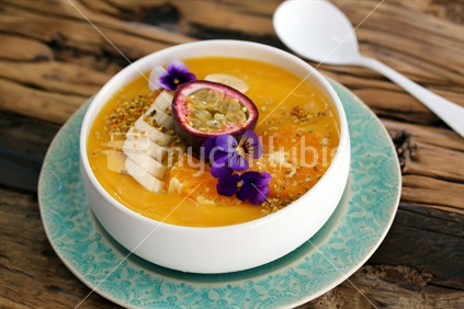 Banana custard with passion fruit in a dish on wooden garden table.