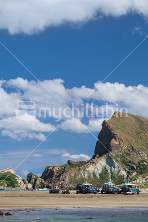 Rugged face of Castle Rock, crayfishing boats in the midground, Castlepoint, Wairarapa
