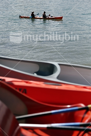 A background of recreational kayakers seen across an out-of-focus foreground of hire paddle-boats.