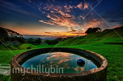 Sunset from One Tree Hill looking towards the western suburbs with the worlds colours reflected in the water trough