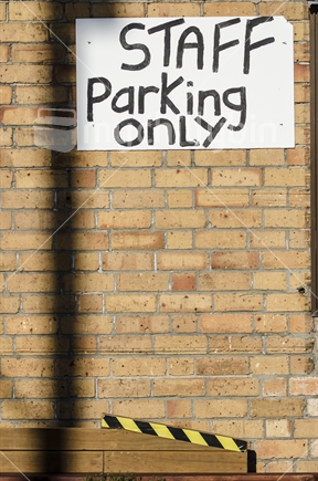 Hand painted staff parking only sign on a brick wall