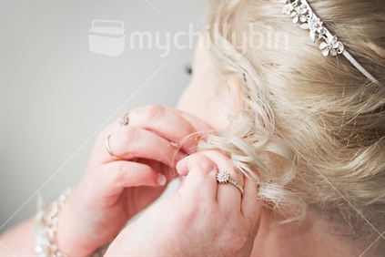 Woman putting on earrings before her wedding (selective focus)