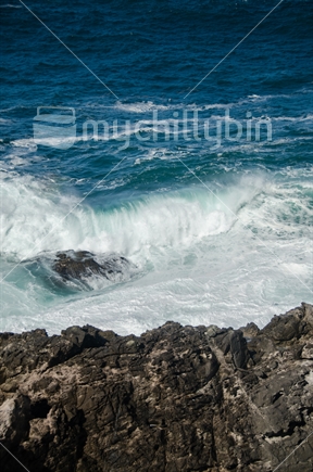 Waves crash on the rocks at the point in Hahei.