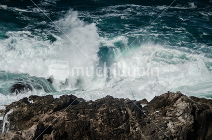Waves crash on the rocks at the point in Hahei.
