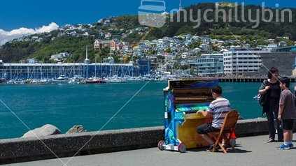 A man plays the piano busking on a sunny day on Wellingtons Lambton quay