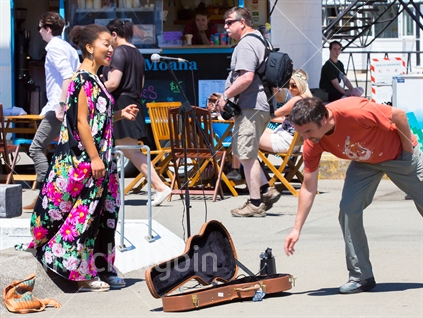 A passerby shows his appreciation of the buskers talent on the Wellington waterfront