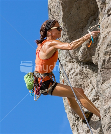A woman displays the strength required to negotiate the rock climb on the face of Mt Maunganui in the BOP