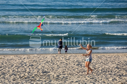 A young girl flies her kite at the beach on a sunny autumn day