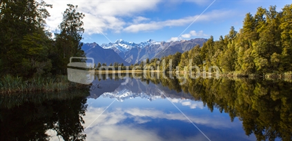 The native bush and mountains of the southern alps reflected in the still waters of Lake Matheson