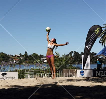 Julia Tilley jumps high to serve in the Hamilton Open Beach Volleyball competition