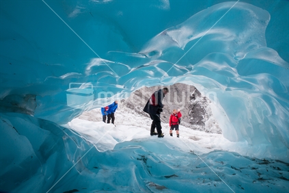A man walks through a blue ice tunnel on the Franz Joseph glacier