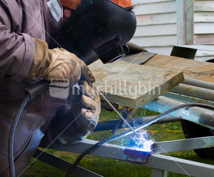 Image of a man welding steel on a trailer