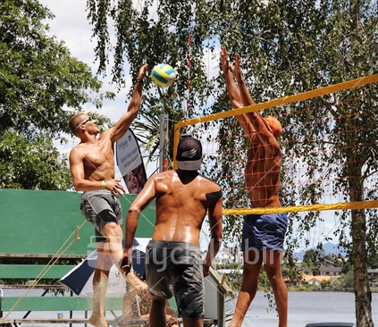 Men''s player competes against a tall block in a beach volleyball game