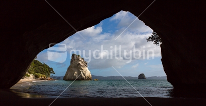 Rock formations in the sea are framed by the rock outline of Cathedral Cove