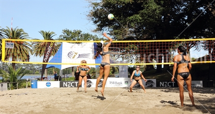 NZ player jumps high to spike the ball during beach volleyball competition