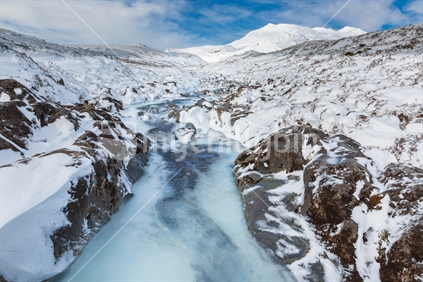 The partially frozen river on the track to the Taranaki Falls in the Tongariro National park after a heavy snow fall