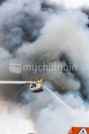 Firefighters spray water from above into the building
