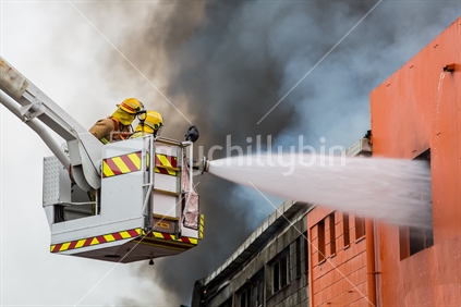 Close-up photo of Firefighters blasting water into a buiilding