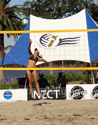 Woman's player serves during beach volleyball game in Hamilton