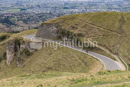 A sole cyclist rides down the access road from the summit of Te Mata Peak on a winters day,