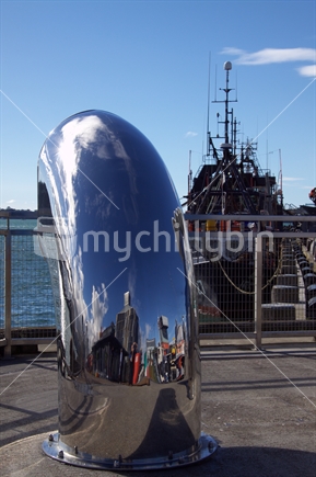 Reflection of the Auckland Wynyard quarter information centre in a quayside funnel with a fishing boat