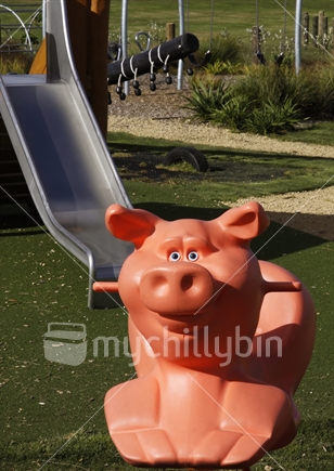 Part of the playground at Sanders Reserve, an Auckland City Council recreational property. Foreground of pig children's toy with a slide in the background. 