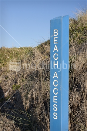 Beach access sign next to dunes
