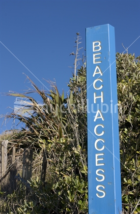 Beach access sign next to coastal plants