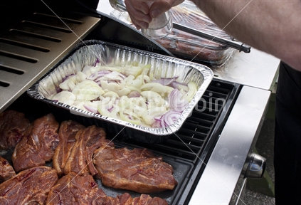 Lamb chops and onion cooking on a BBQ