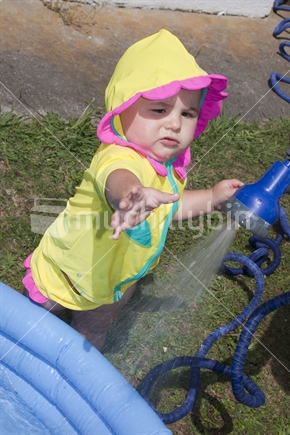 Toddler playing with water from hose