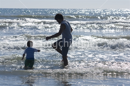 Father and son playing in the waves at beach