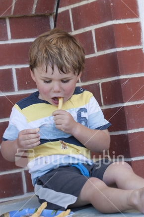 Young boy, eating chips.