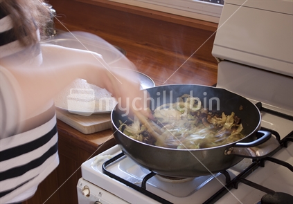 Woman cooking stir fry on gas stove