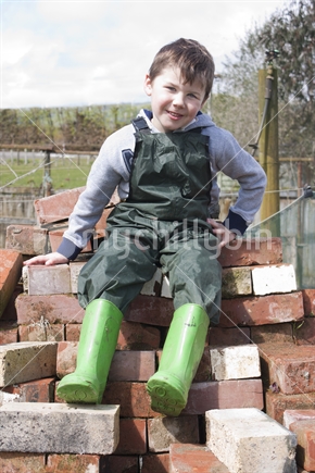 Little boy on a pile of bricks on a farm
